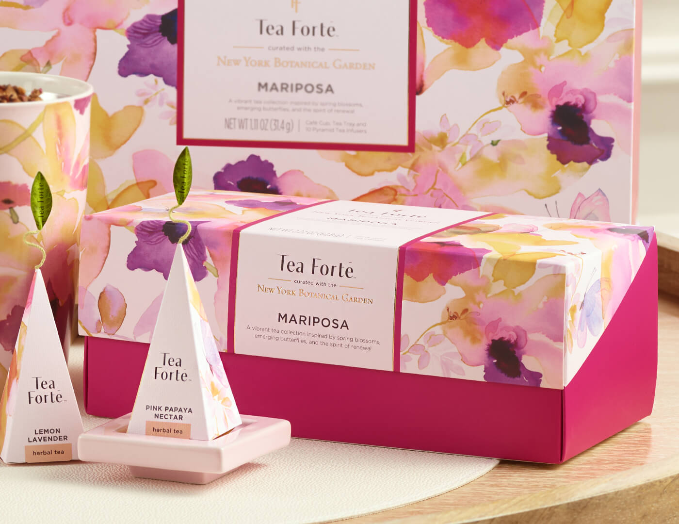 Mariposa Presentation Box of 20 pyramid tea infusers, closed  on a table with a tea infuser and pink tea tray