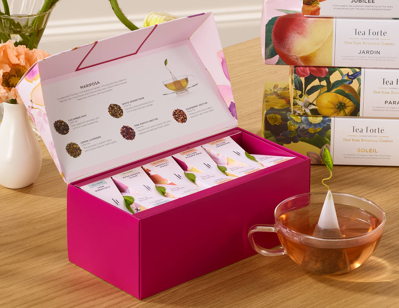 Mariposa Presentation Box of 20 pyramid tea infusers, open  on a table with a glass cup of tea