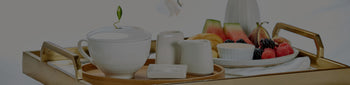 Cafe Cup presentation on a tray on a bed with breakfast fruit