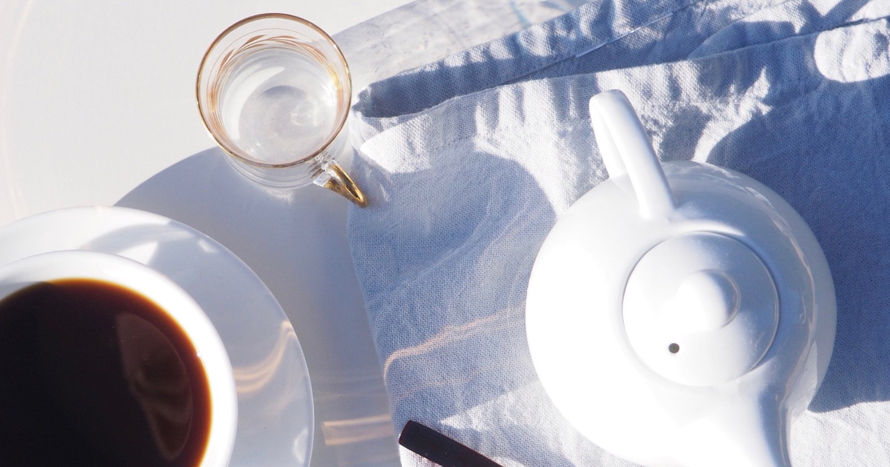 White teapot and cup of tea on a white napkin