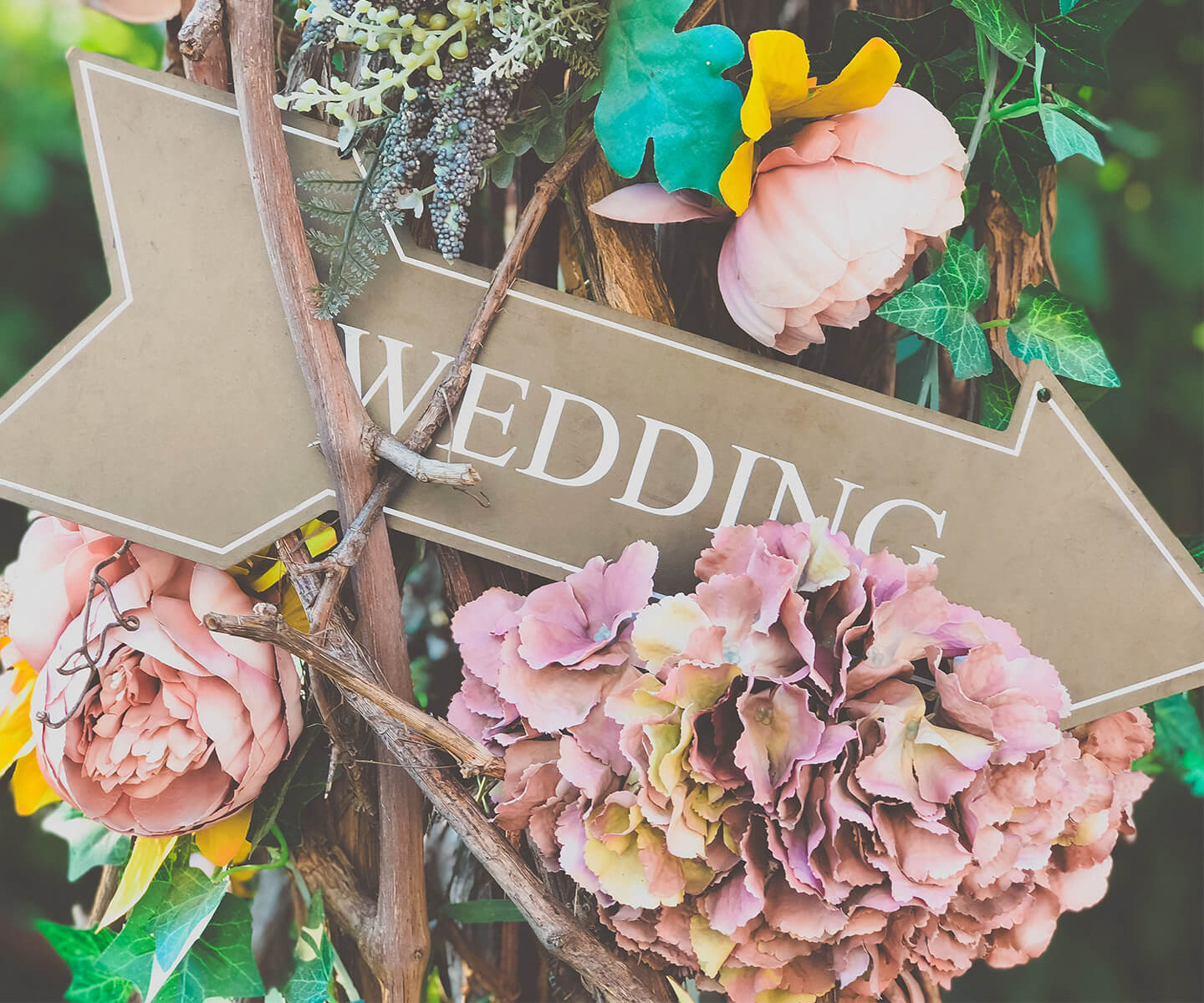 Wedding sign on a post with woven plants and flowers