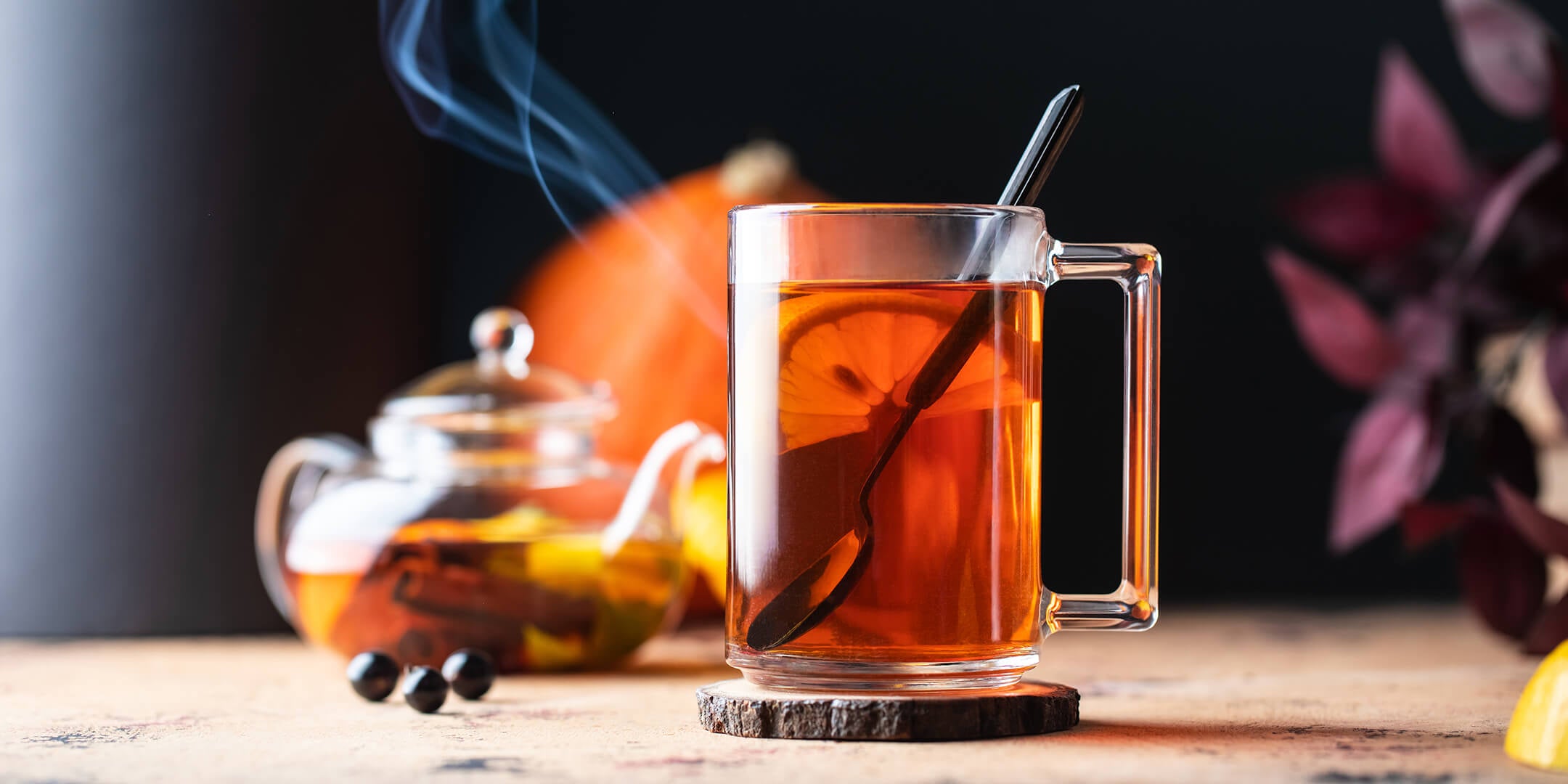 Glass mug of steaming Earl Grey with a glass teapot in background