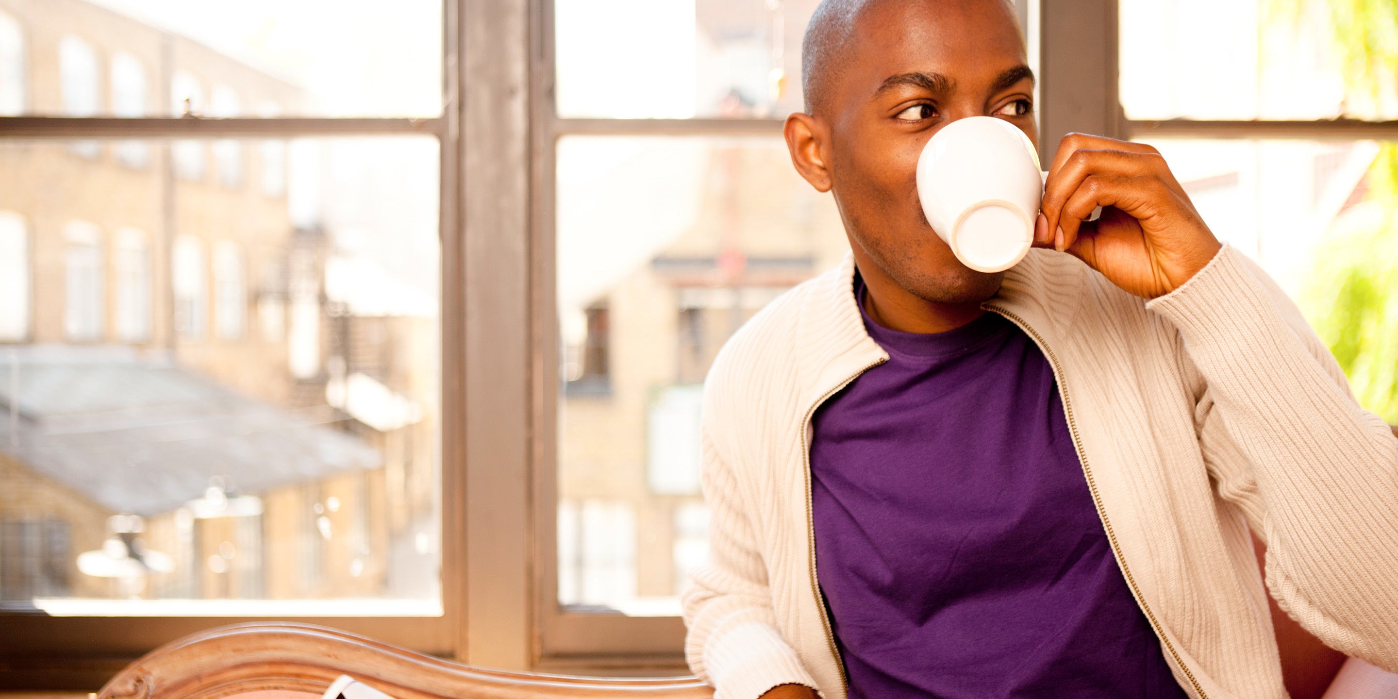 Man drinking tea at a table by a window