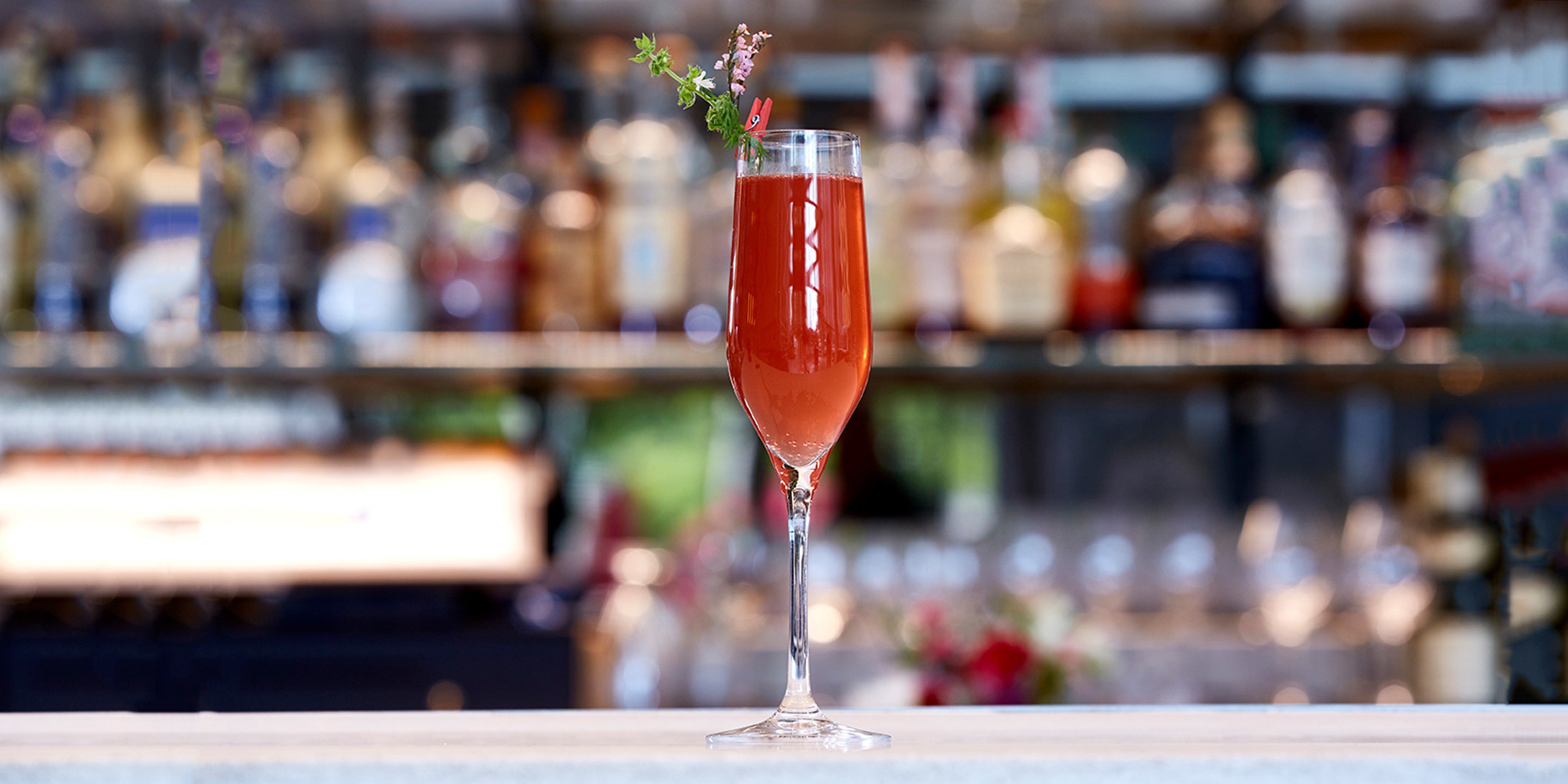 Raspberry Nectar Fizz in a champagne glass on a bar