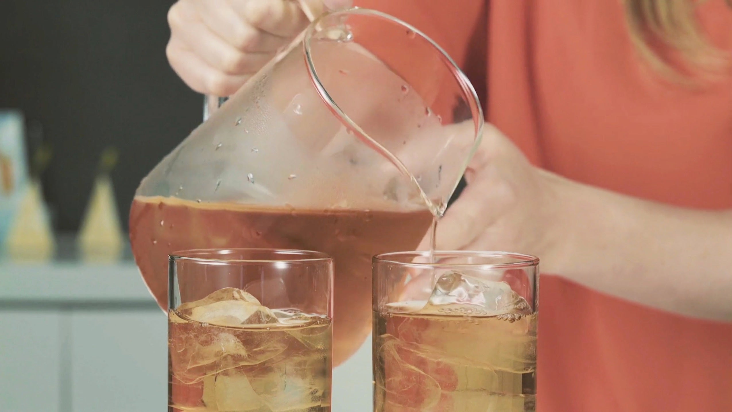 Pouring iced tea from a pitcher set into tall iced tea glasses