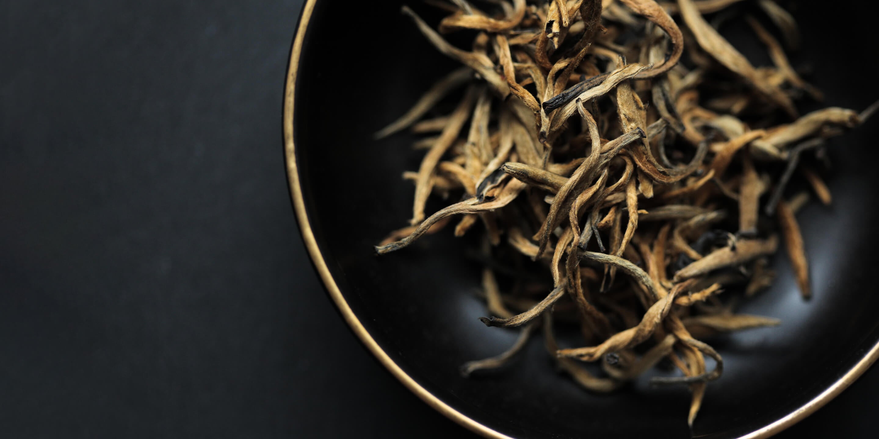 Loose leaf tea in a dark ceramic bowl