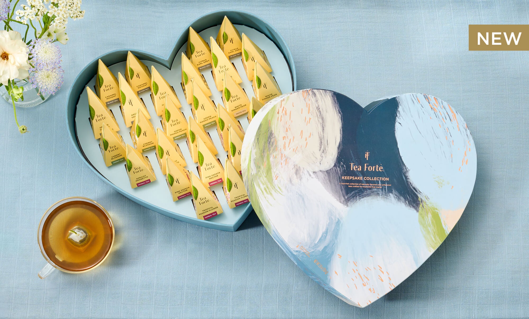 Keepsake Heart on a blue background, open revealing 26 pyramid tea infusers with flowers