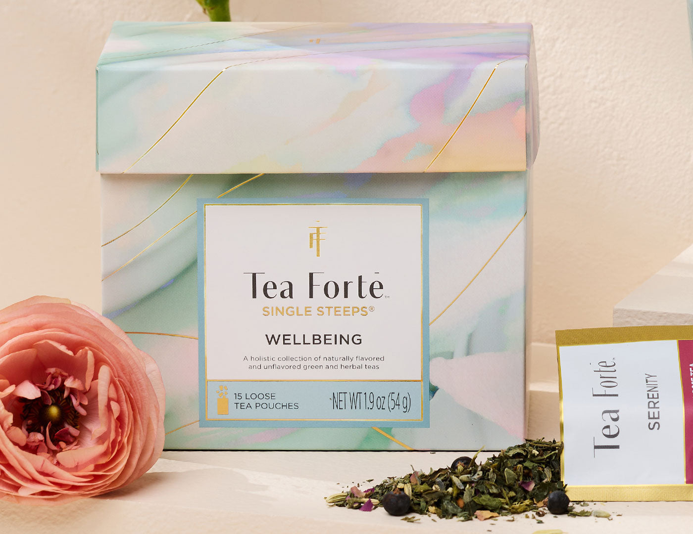 Tea Forte Wellbeing Single Steeps Sampler with a pink flower and loose tea leaves on a light background