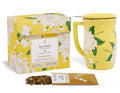 Yellow box with white hydrangea floral pattern, matching yellow mug with lid, and loose tea pouch with dried tea leaves.