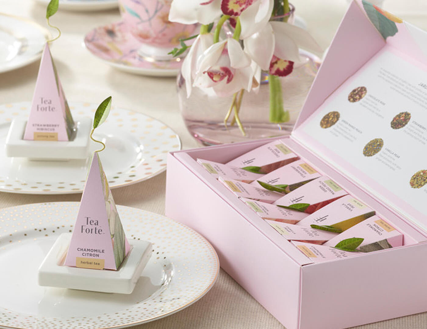 Jardin Petite Presentation Box open on formal dining table set with white plates, pink infusers and white flowers