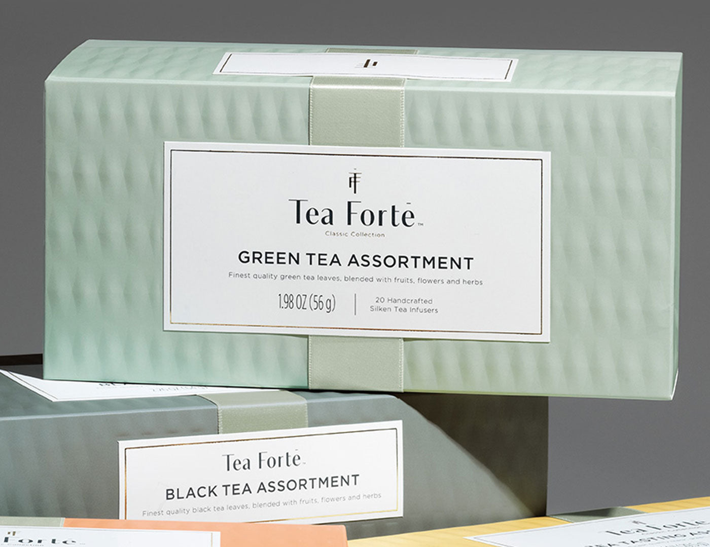 MAIN PDP |  Green Tea Assortment Presentation Box of 20 infusers, stacked on top of other boxes 