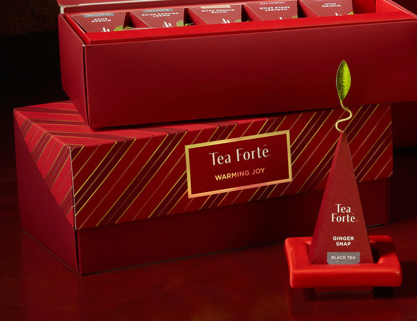 Presentation Box Warming Joy, of 20 tea infusers, open and closed, with a Tea Tray and pyramid infuser on it out front.