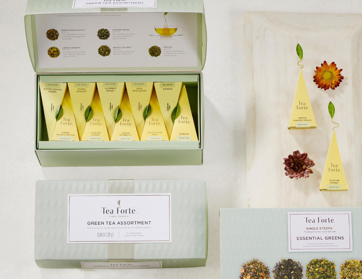 MAIN PDP | Green Tea Assortment Petite of 10 teas  open and closed boxes with infusers and flowers on white table