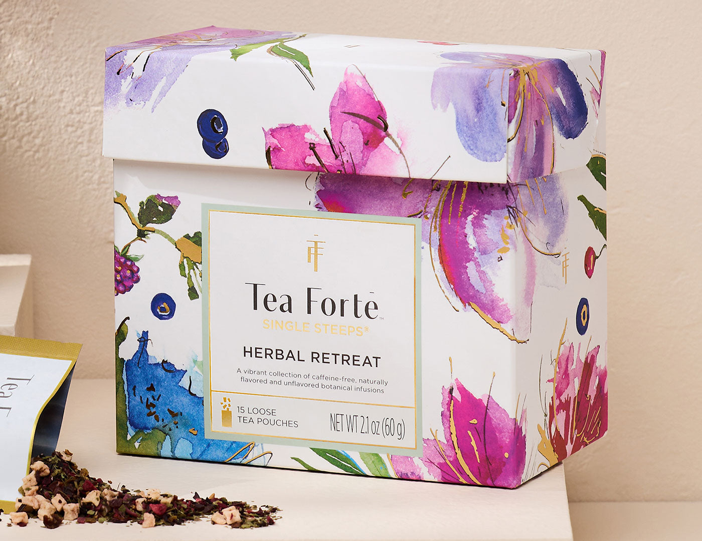 Herbal Retreat Single Steeps Sampler  box, closed iht a loose tea pouch open and pouring out tea