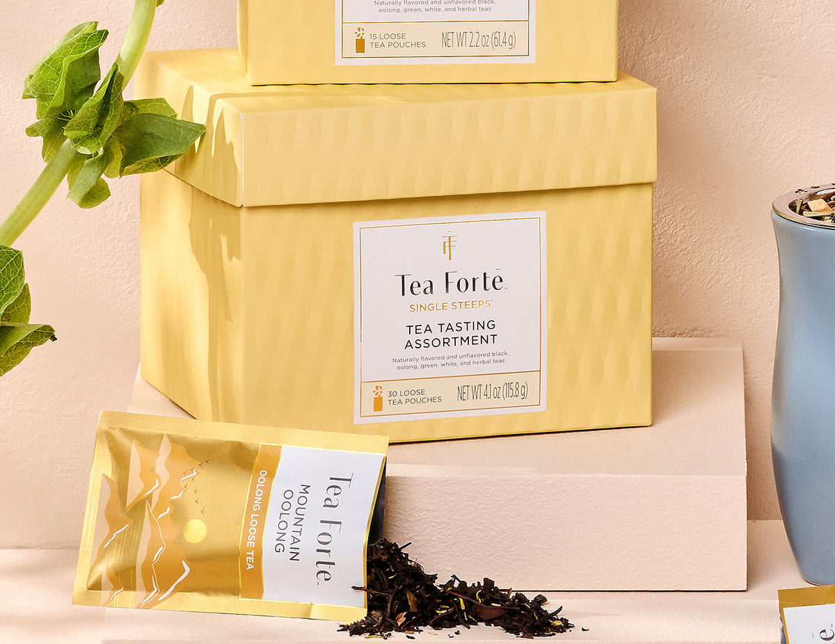 MAIN PDP | Single Steeps tea assortment in a 30count chest of Single Steeps pouches with lid closed and one pouch spilling out tea