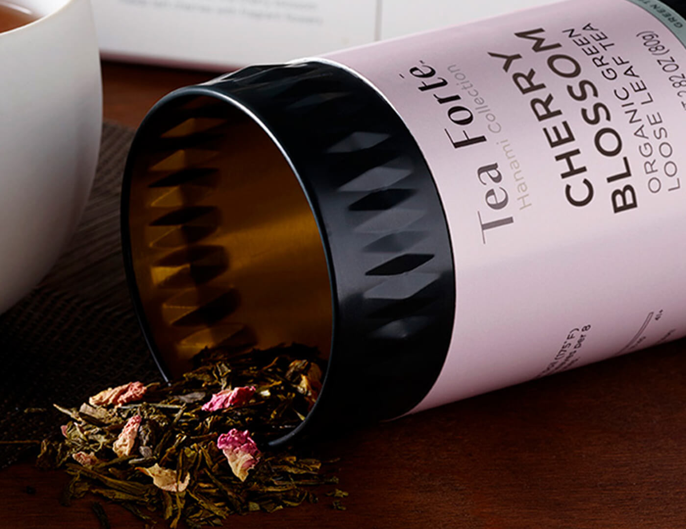 Cherry Blossom Loose Tea Canister lying down spilling out green tea with pink petals