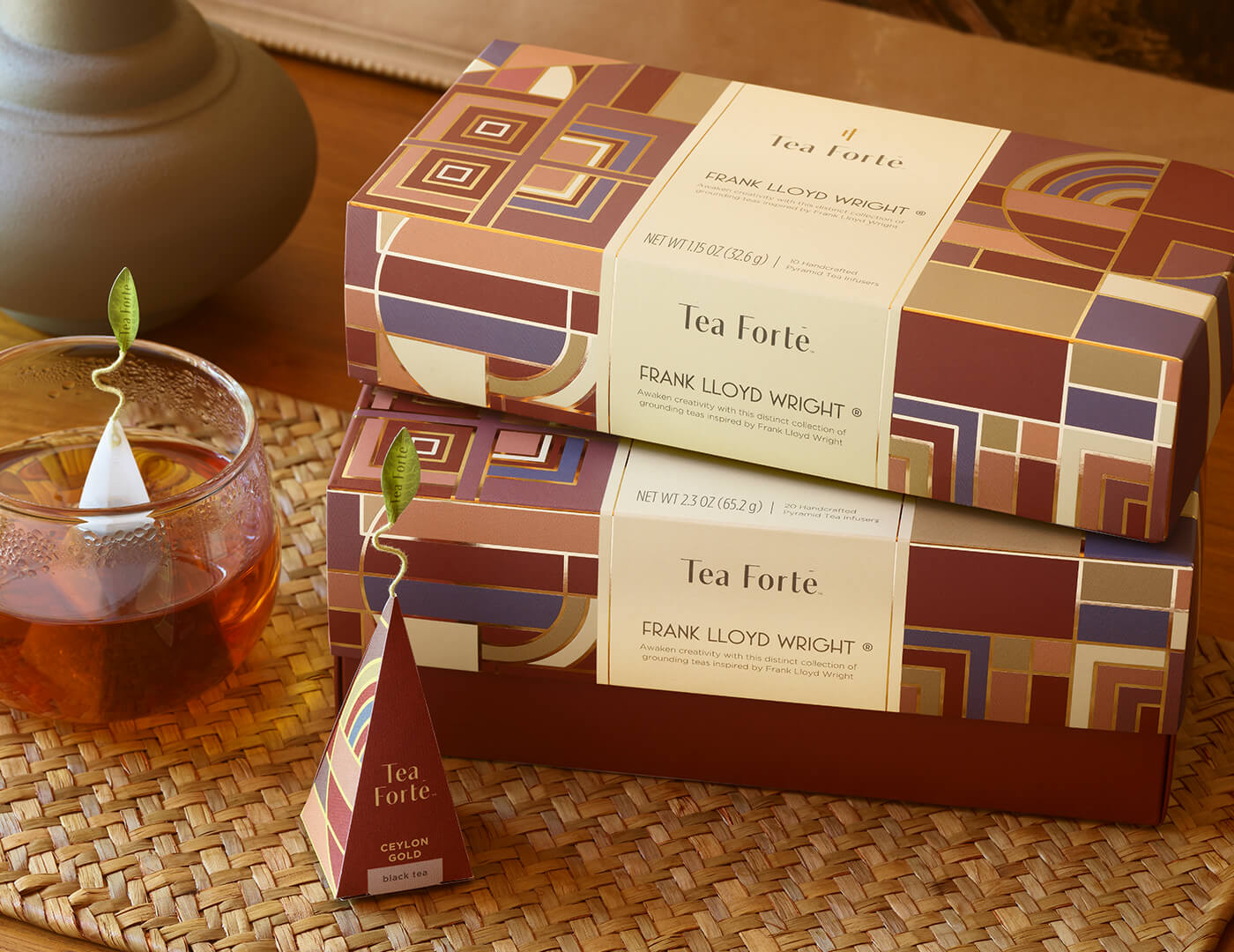 Frank Lloyd Wright Presentation Box and Petite, stacked and closed on a table with an infuser and teacup