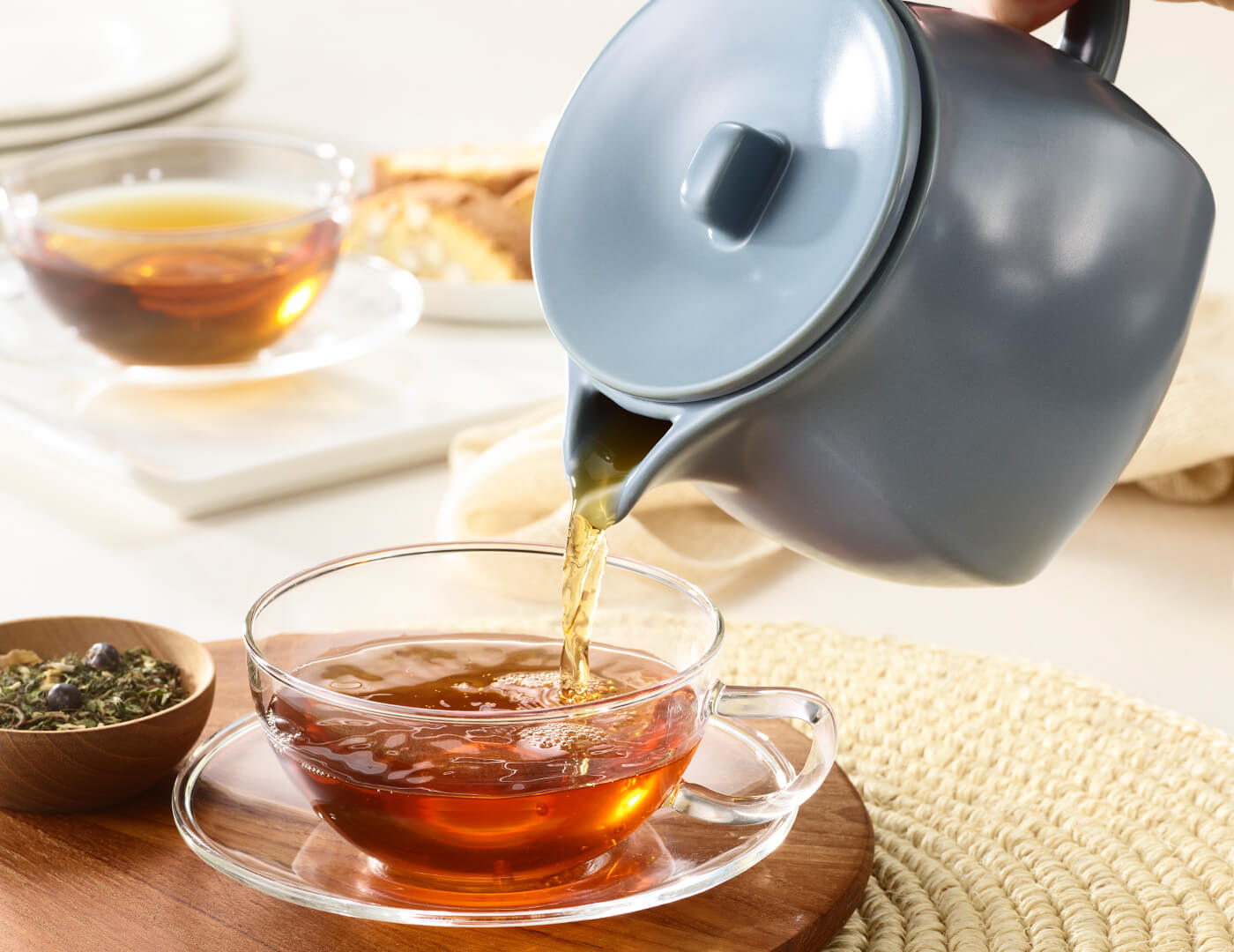 Fiore Stone Blue Teapot with lid pouring steeped tea into a teacup