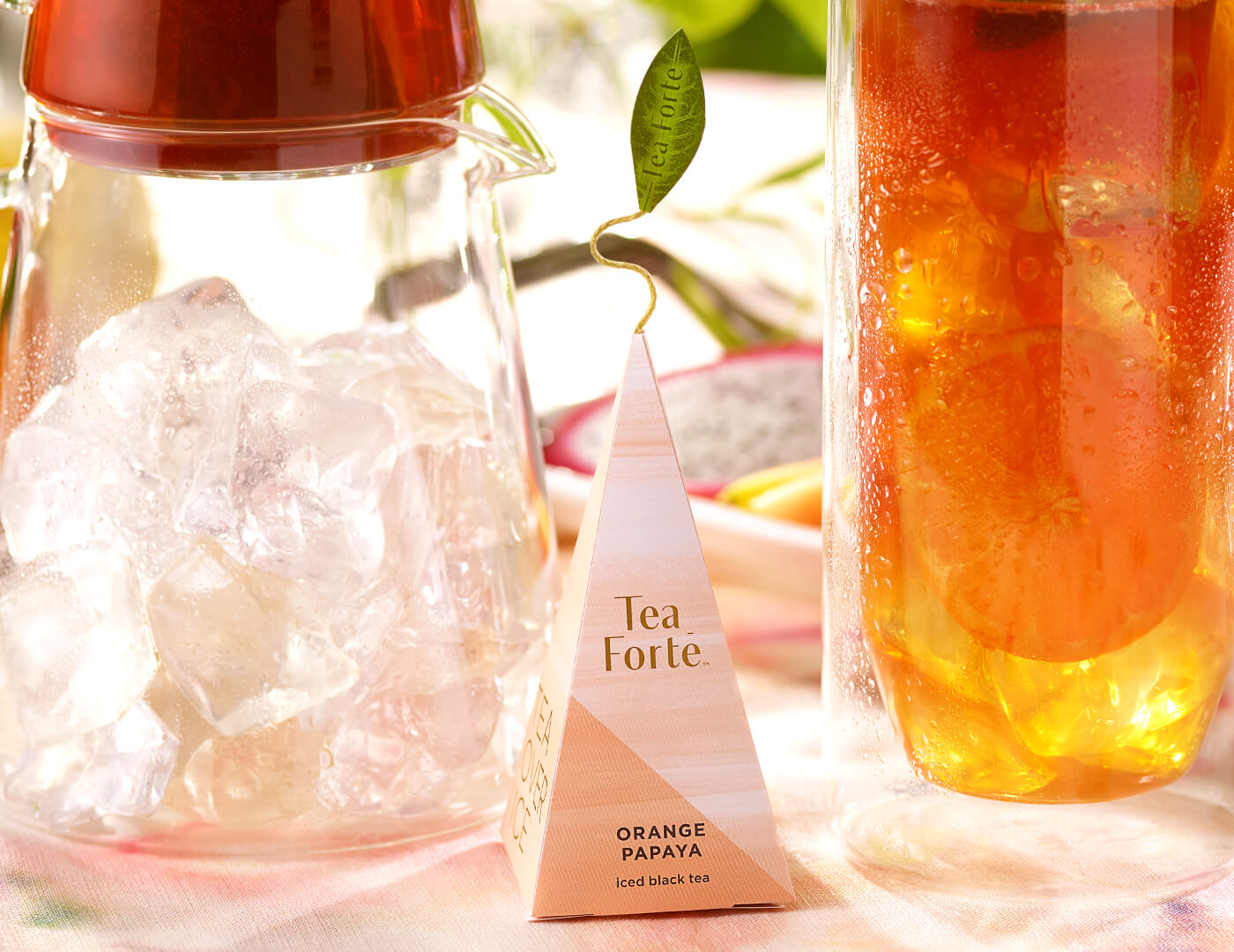 Orange Papaya iced tea pyramid infuser with iced tea glass in background.